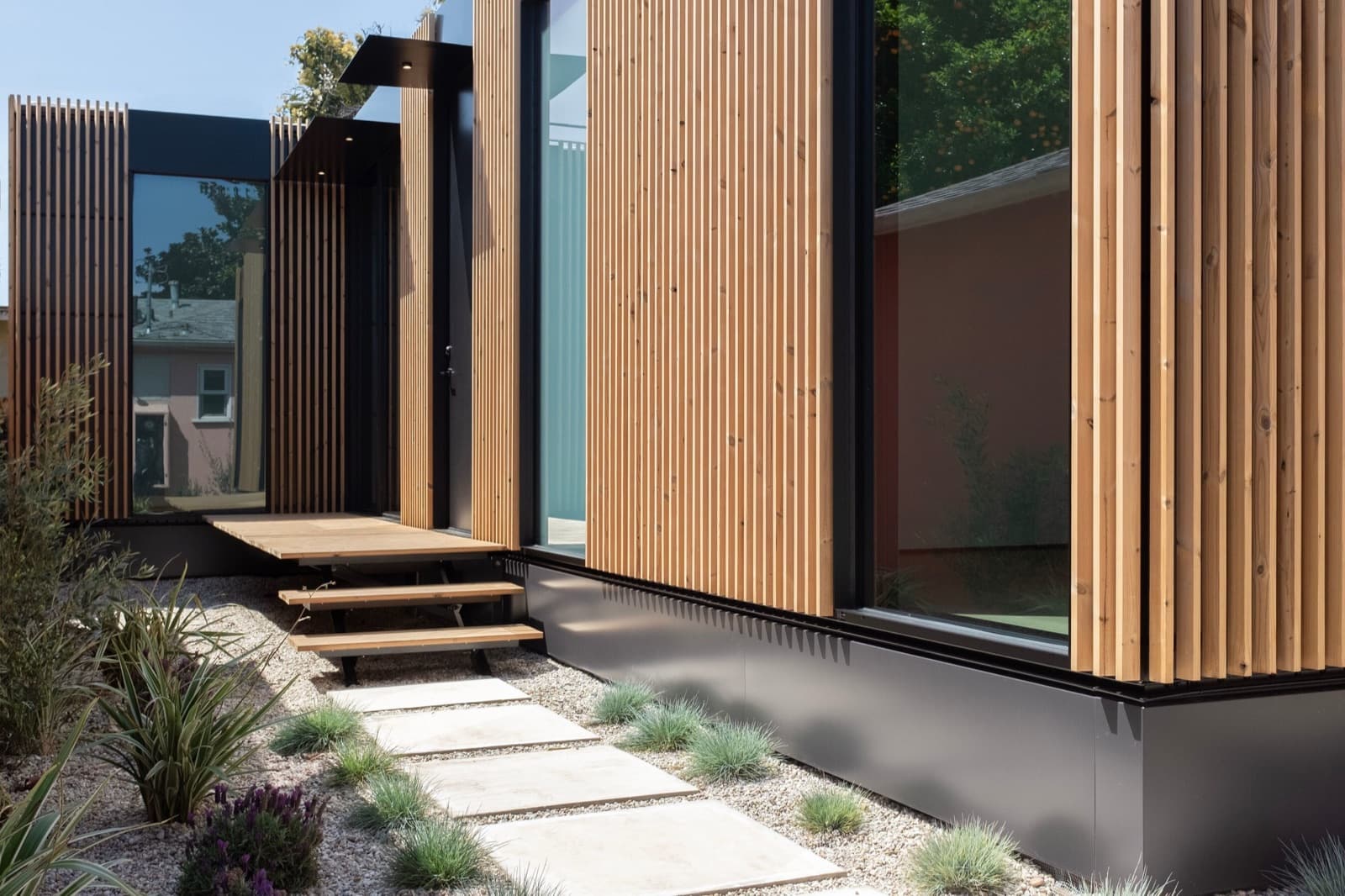 Exterior of a Cover home with vertical wood slats, black steel base and floor-to-ceiling glass