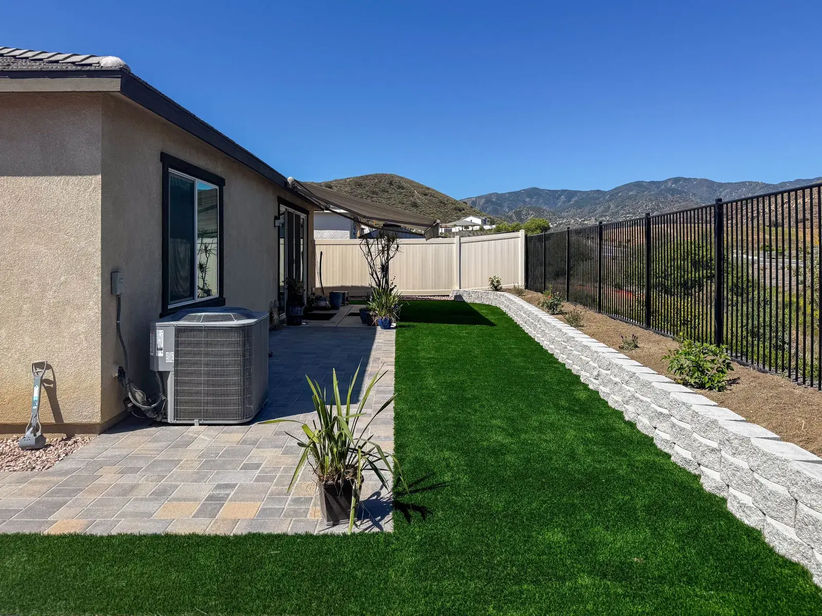 Backyard pavers, artificial turf and block retaining wall