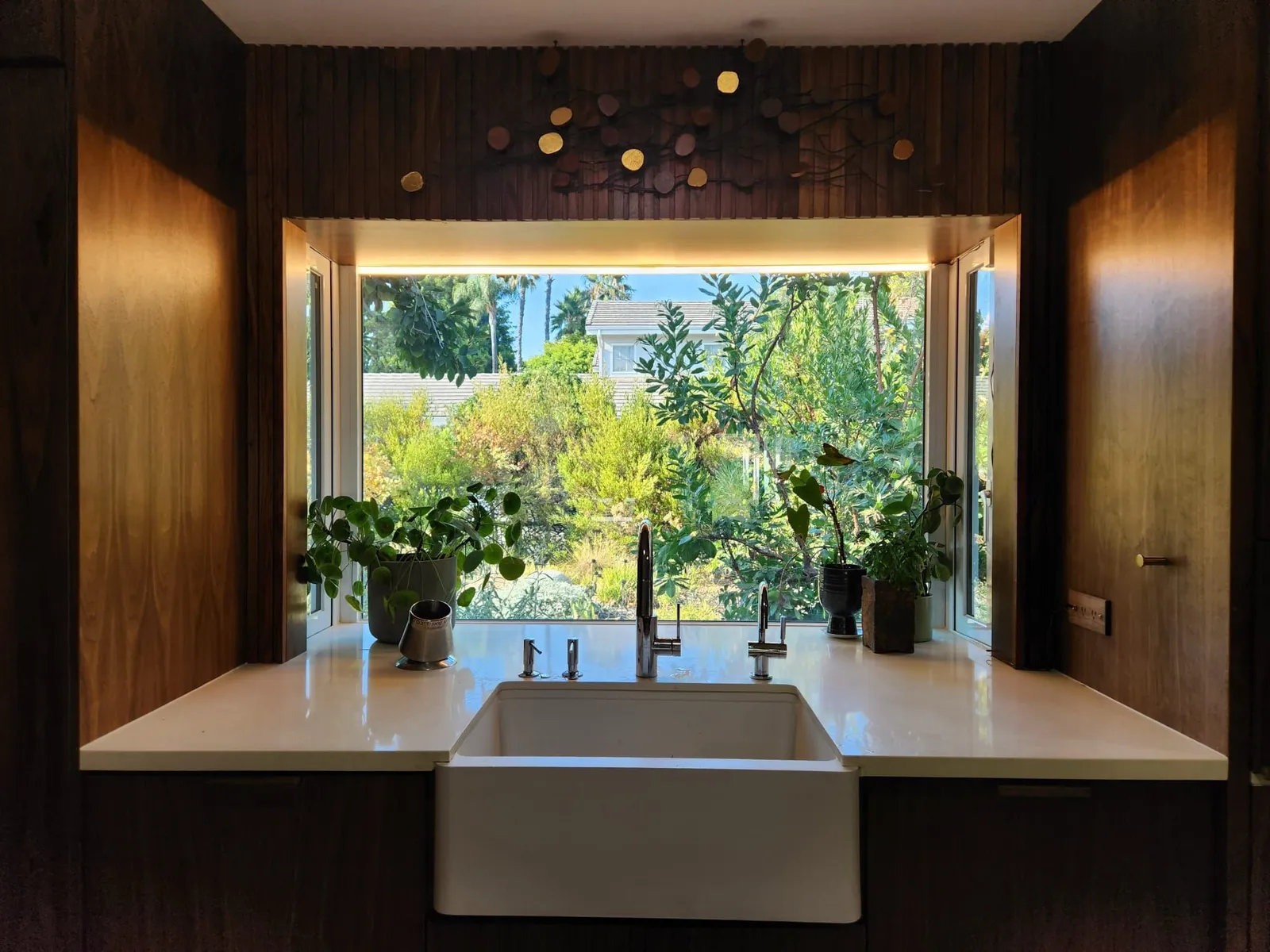 Walnut-paneled kitchen with farmhouse sink under a garden window