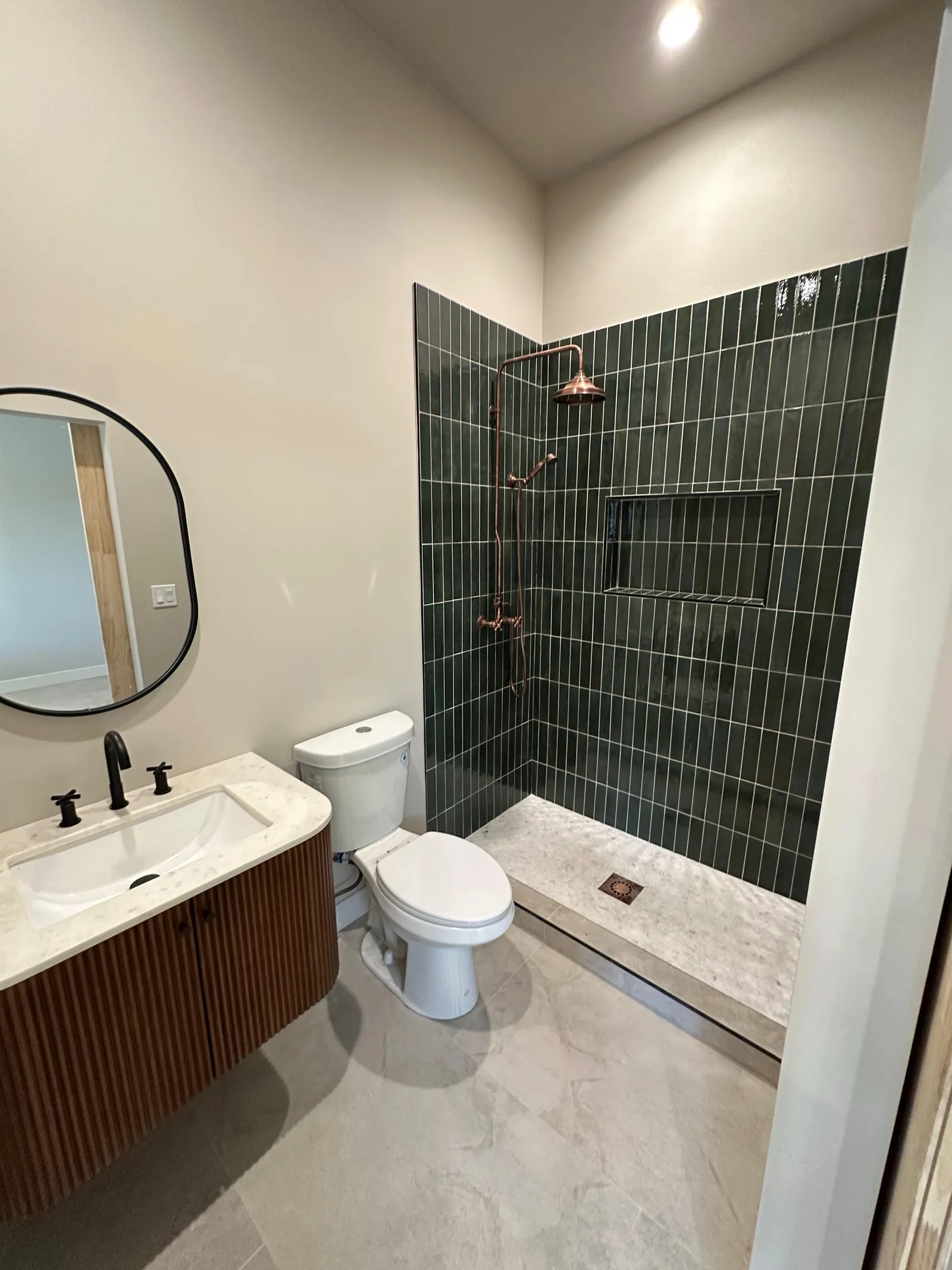 Bathroom with green tile shower and fluted wood vanity