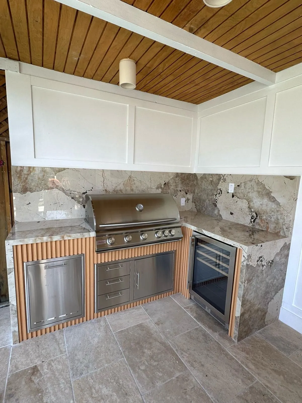 Outdoor kitchen with stone counters and travertine floor