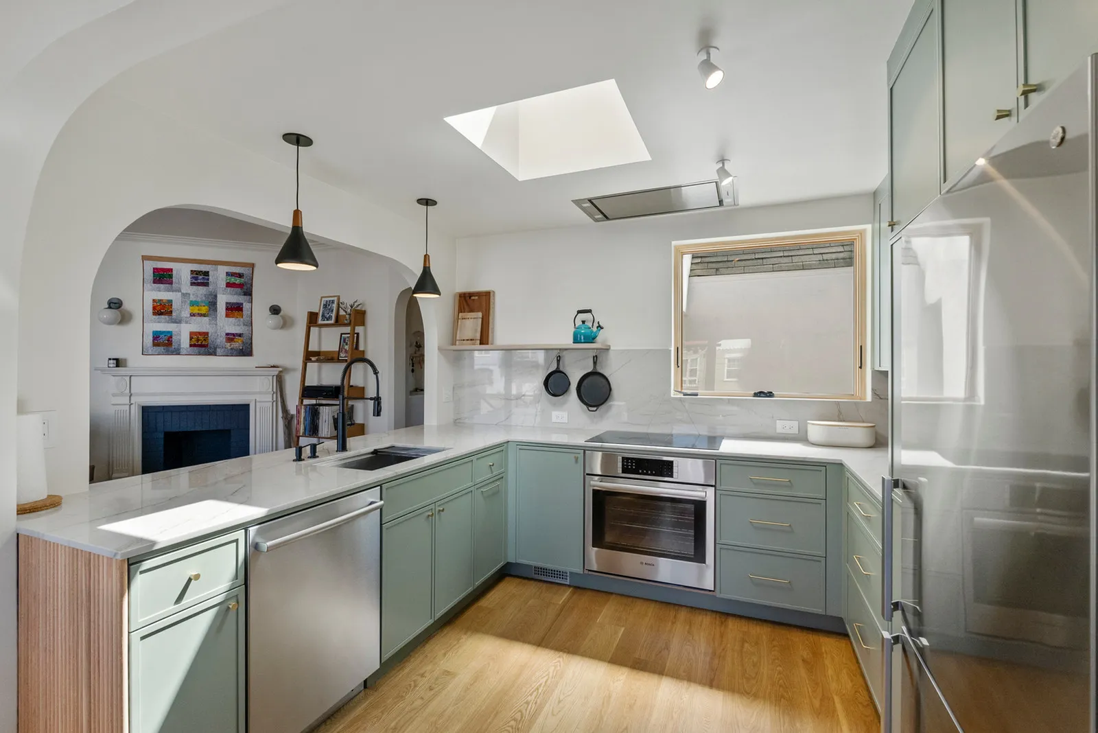 Sunset kitchen remodel with sage-green cabinetry and skylight